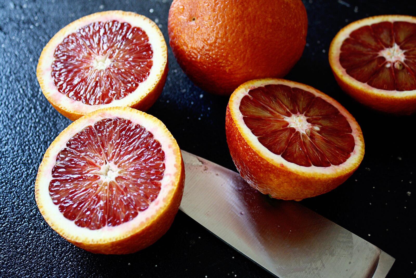 Цитрусовые фрукты в разрезе на столе с ножом