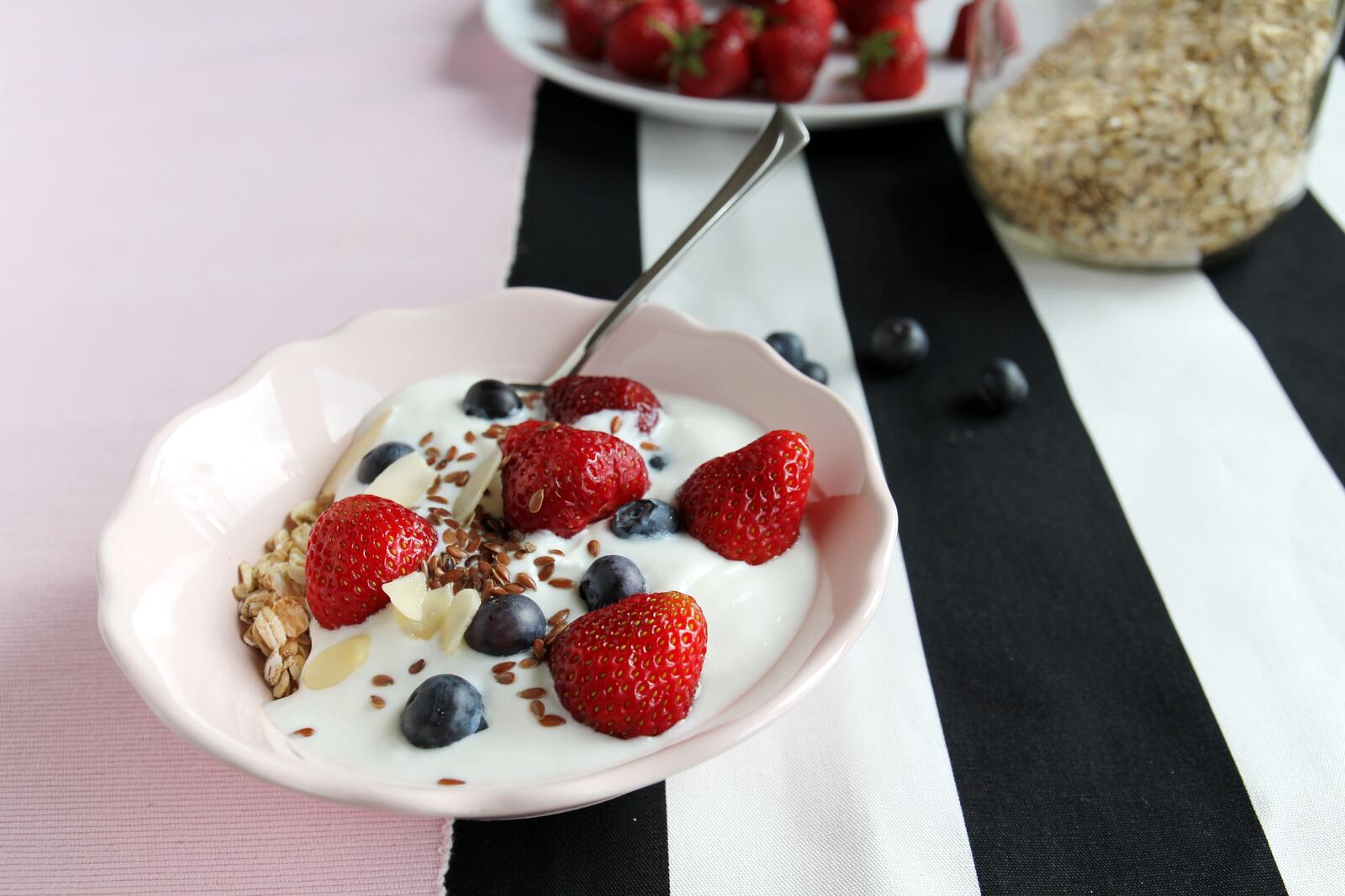Йогурт со свежими дикими ягодами в белой тарелке