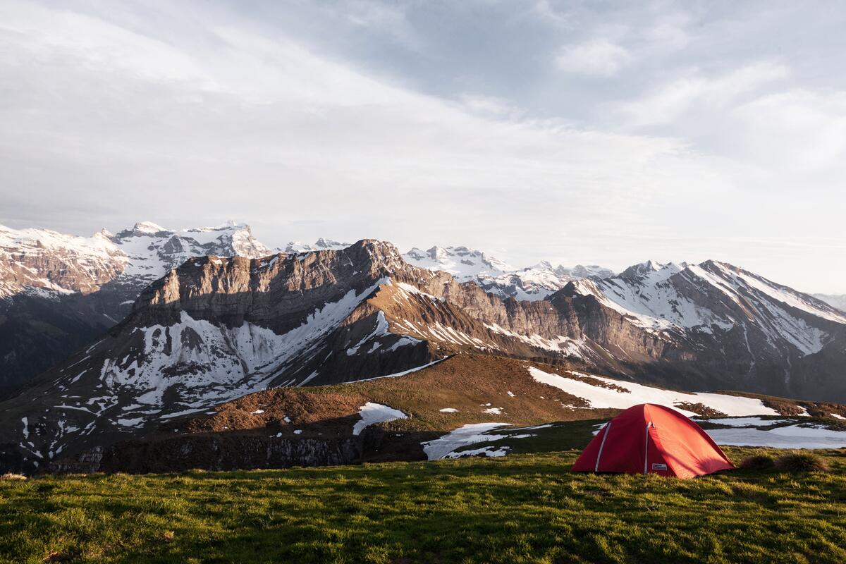 Красная палатка в горах на зеленой лужайке