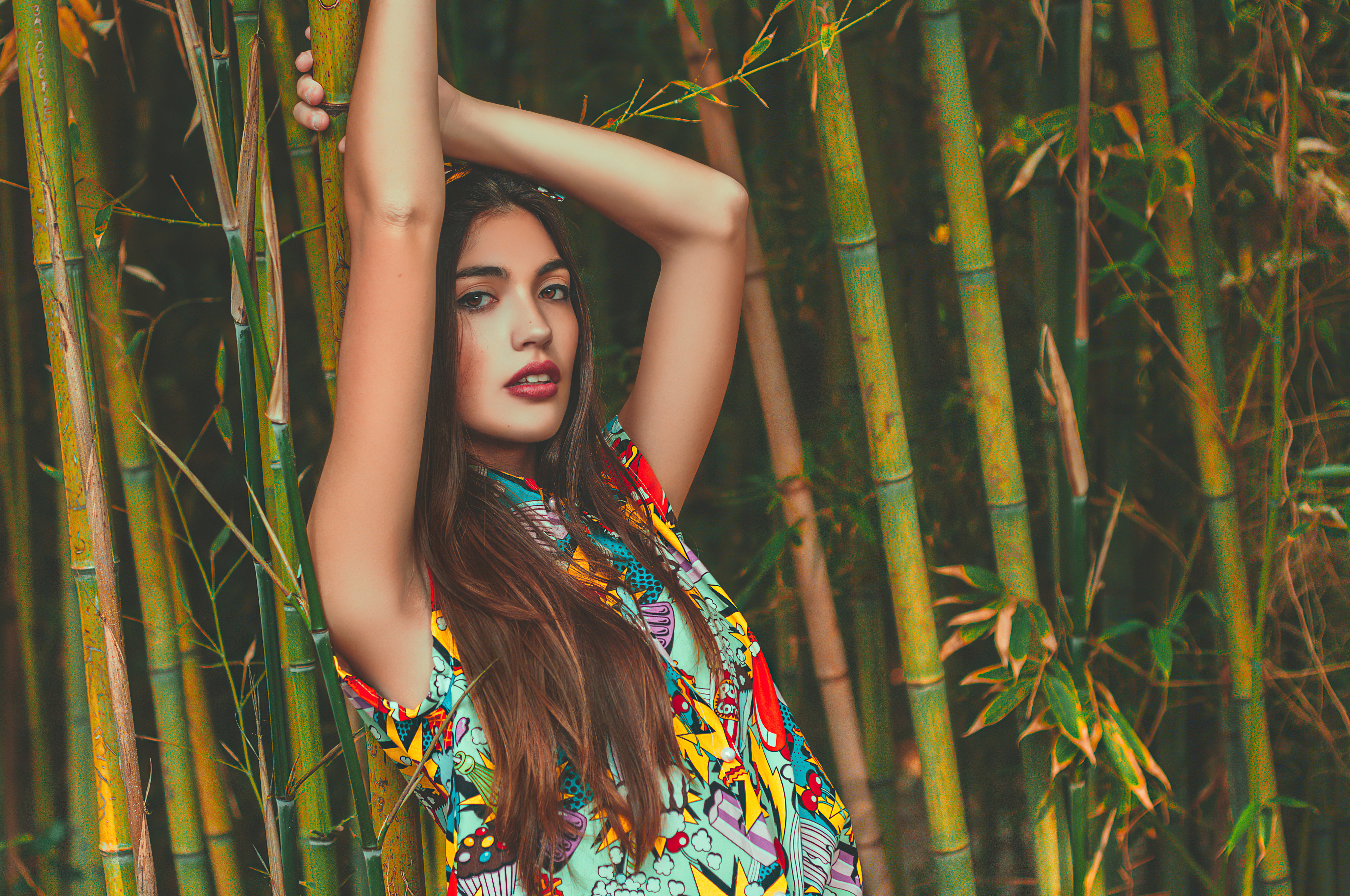 Paula Riba poses in a colorful dress against a background of bamboo