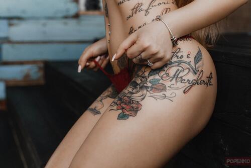 Женское тело с татуировками на ягодицах