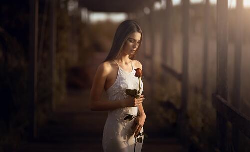 A girl in a white dress with a rose in her hands