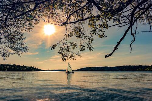 Одинокий парусник на озере солнечным днем