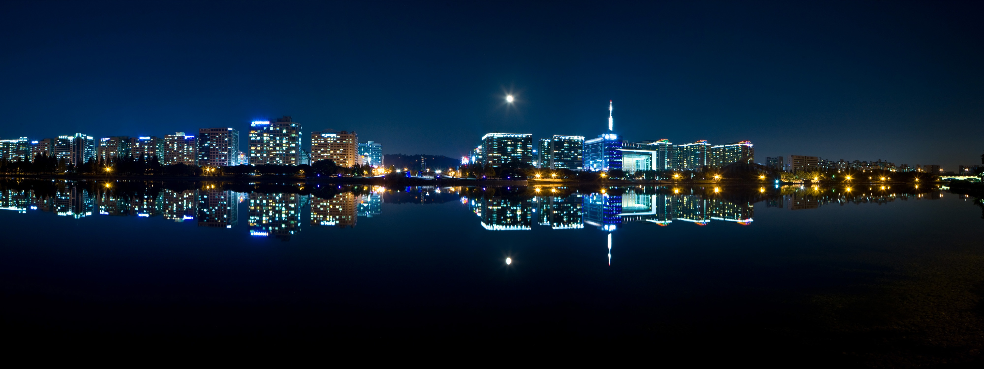 The night city by the sea is reflected in the water