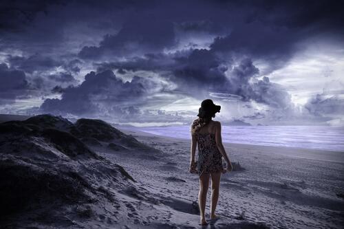 Девушка гуляет по пляжу в плохую погоду