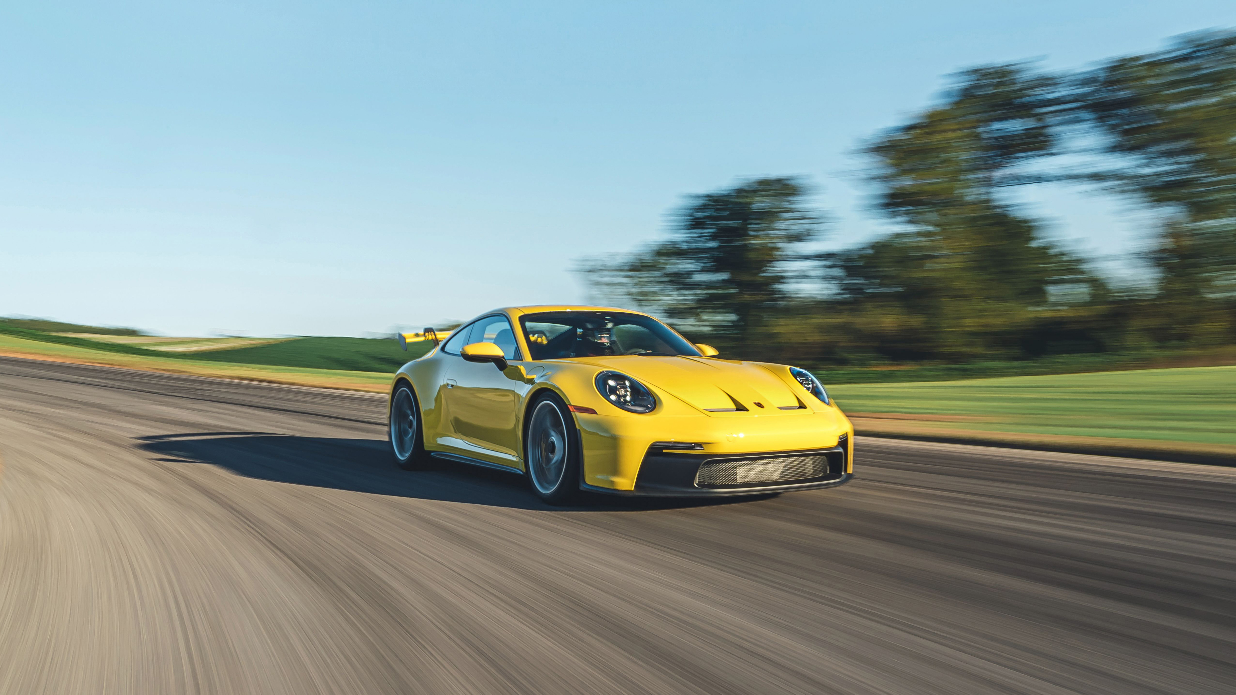 Ярко-желтый Porsche 911 мчится по дороге