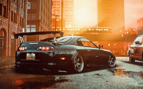 The rear of a tuned Toyota Supra in the city at sunset