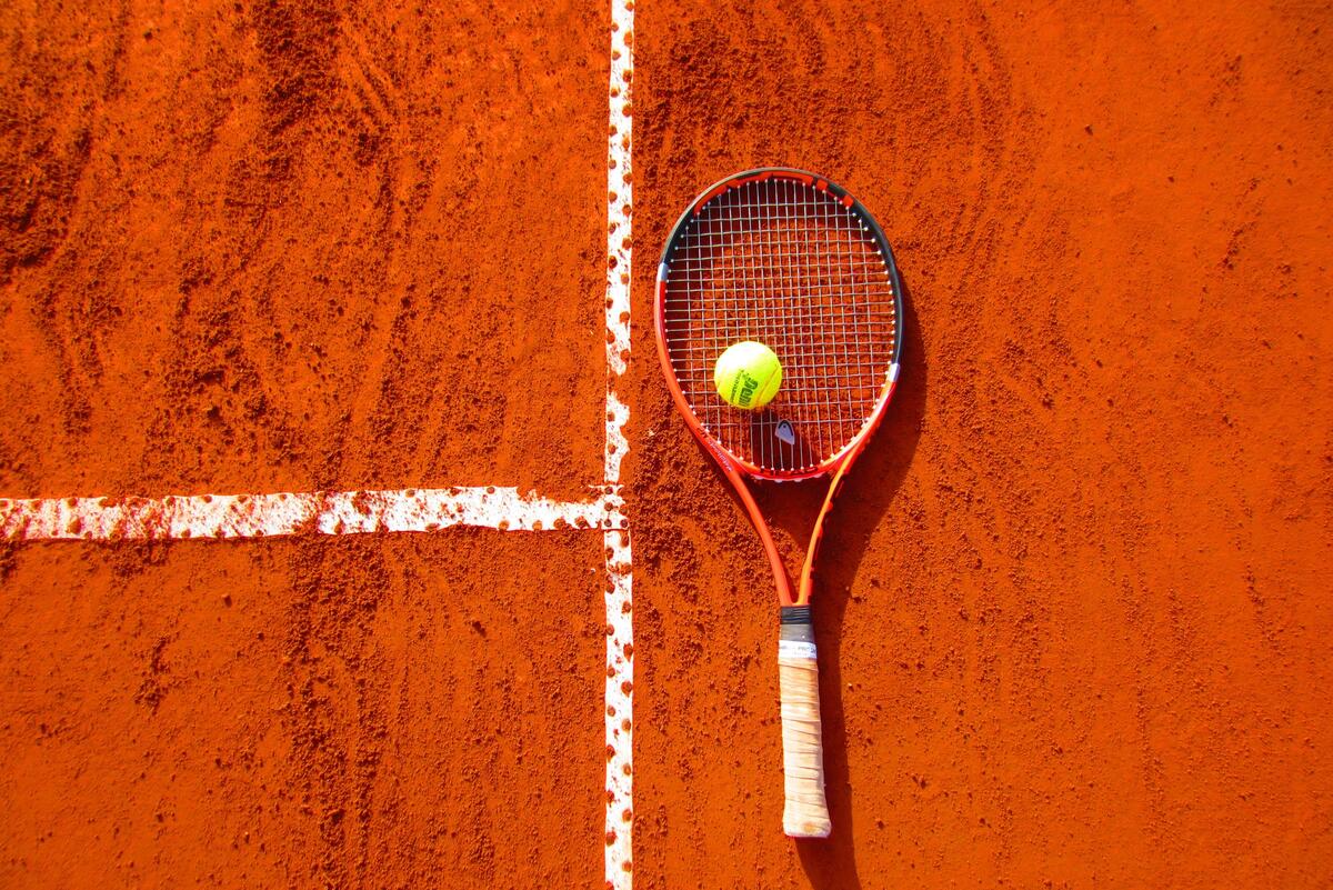 Ракетка для тенниса с теннисным мячом лежат на теннисном поле