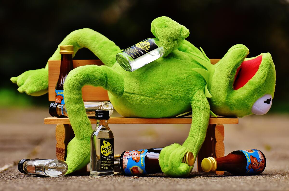 Soft toy frog pretending to be drunk