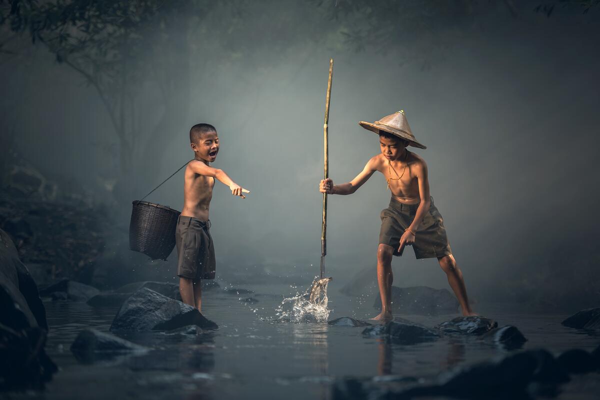 Two Asian boys fishing with a spear.