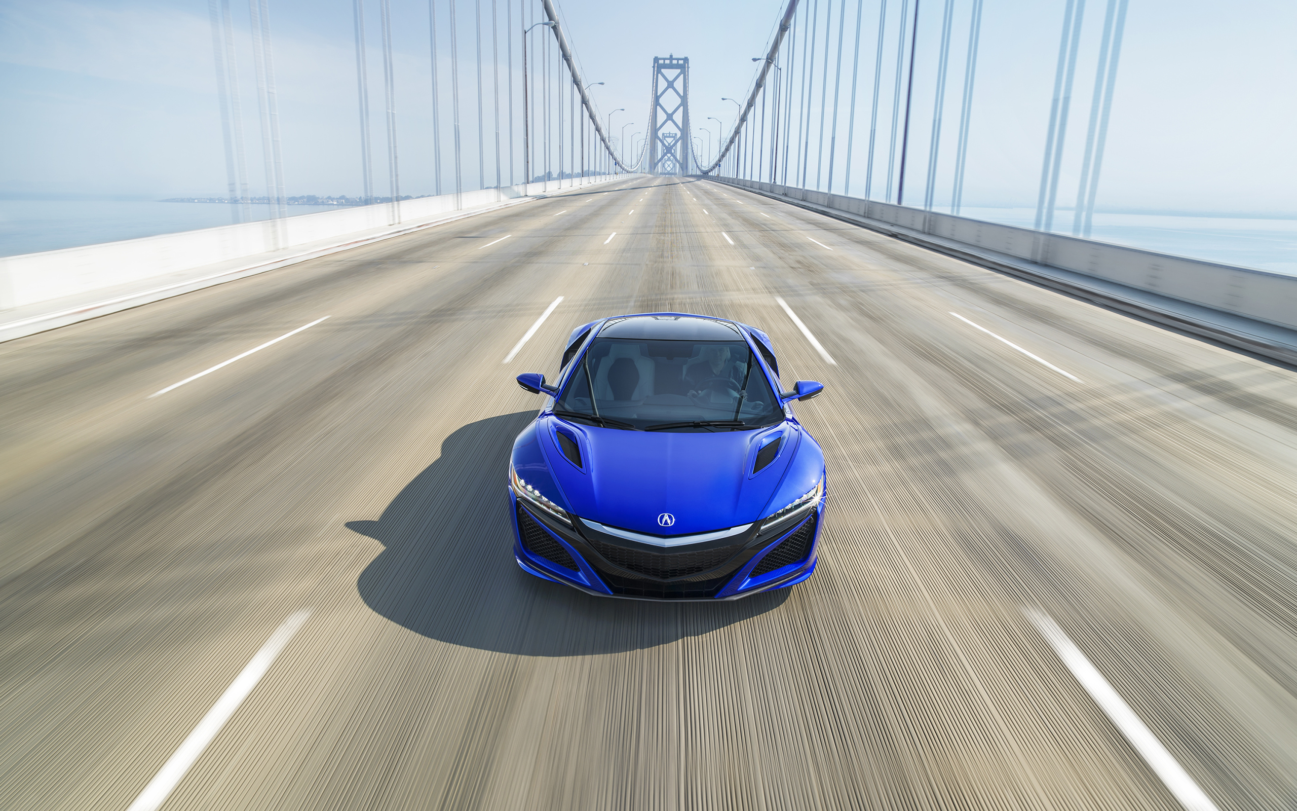 A blue Acura NSX driving over a bridge.