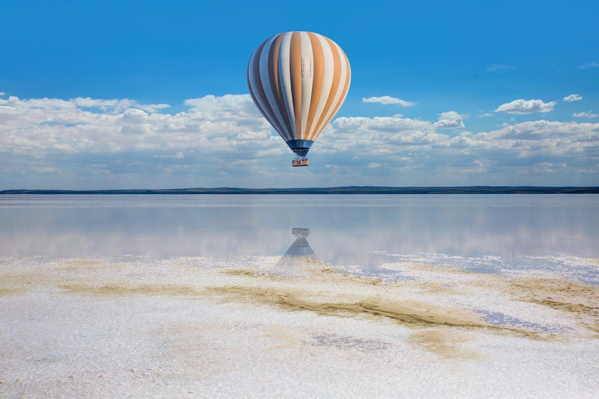 A hot air balloon flying low over the water.