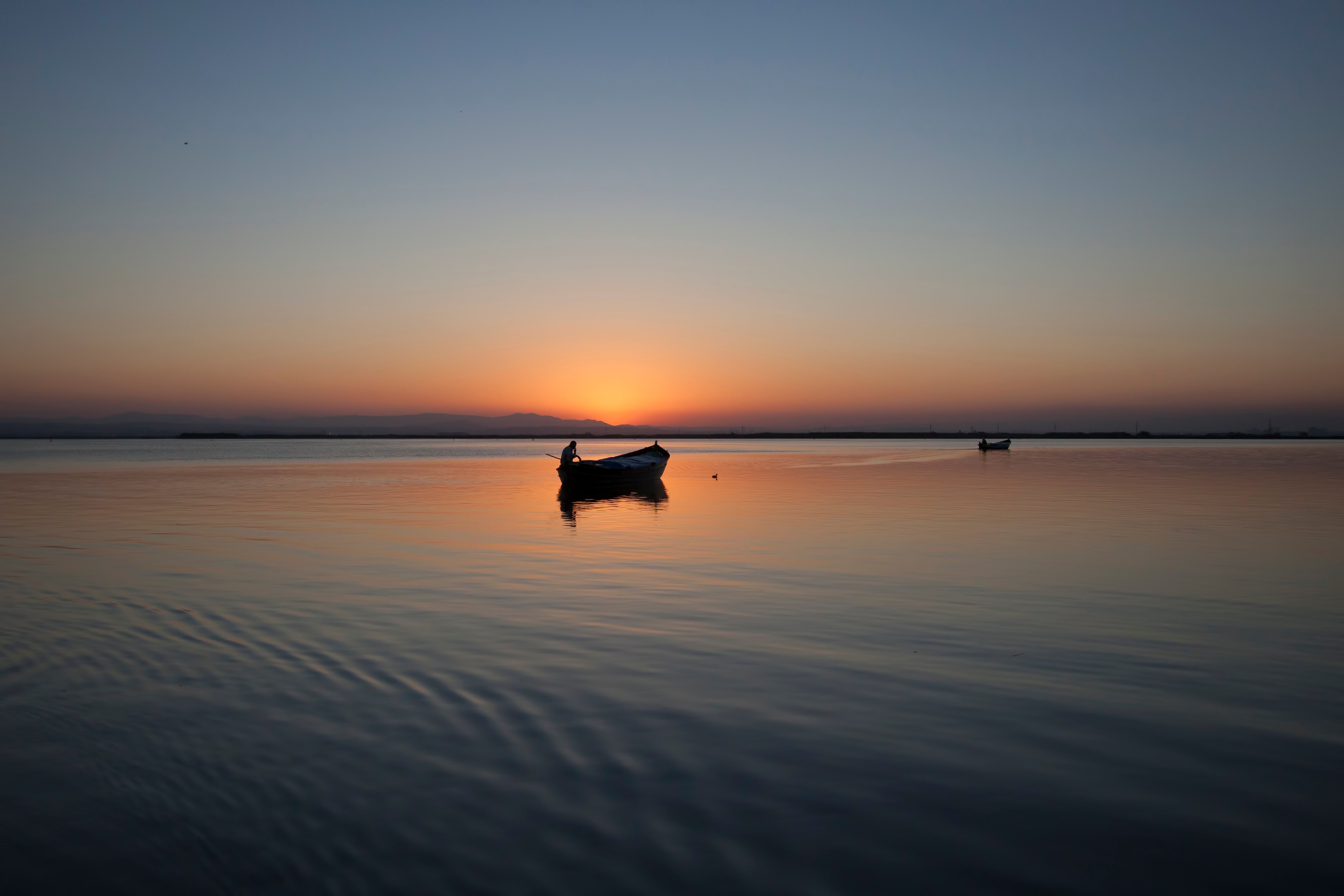 免费照片日落时分湖上小船的剪影