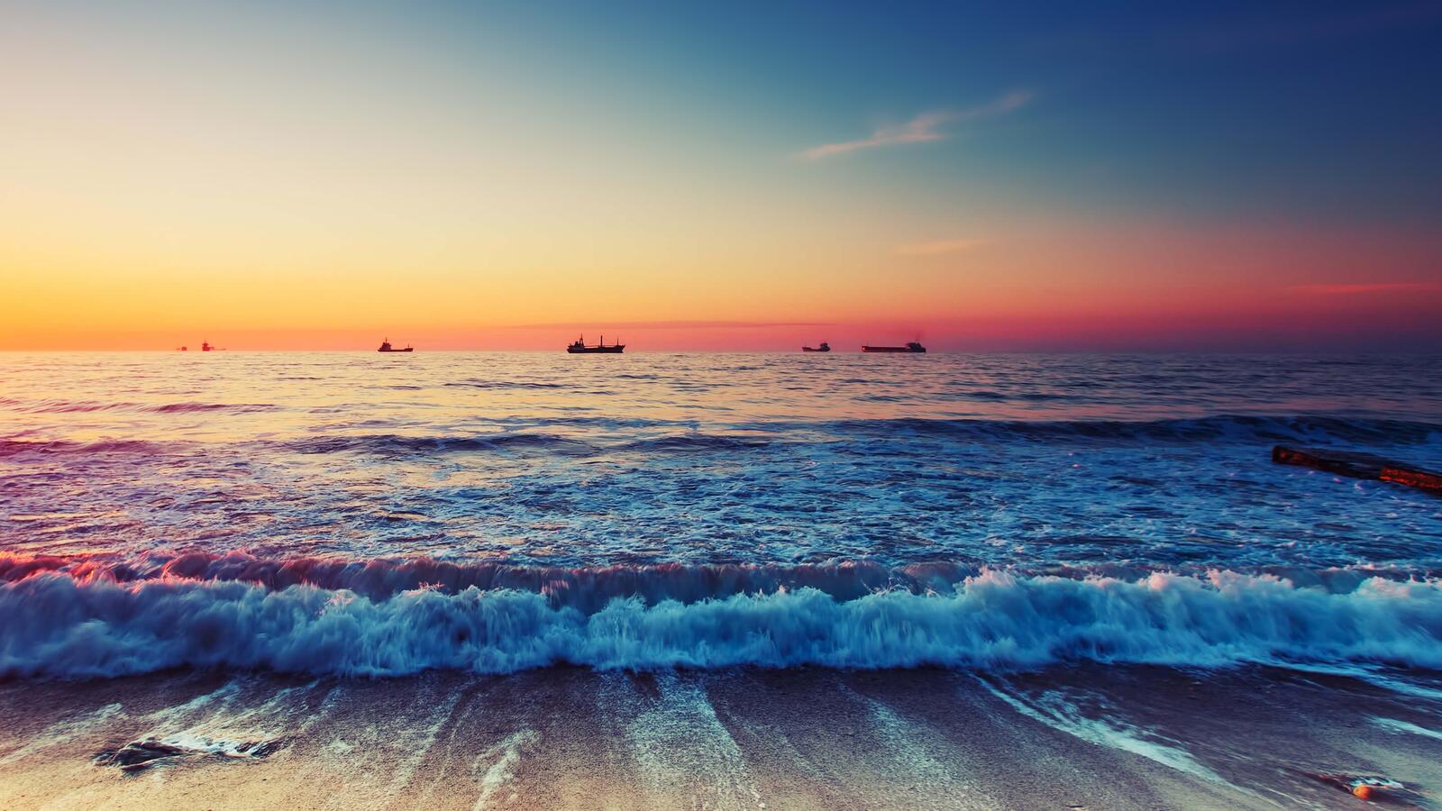 Бесплатное фото Волна на берегу пляжа, а в дали проплывают корабли