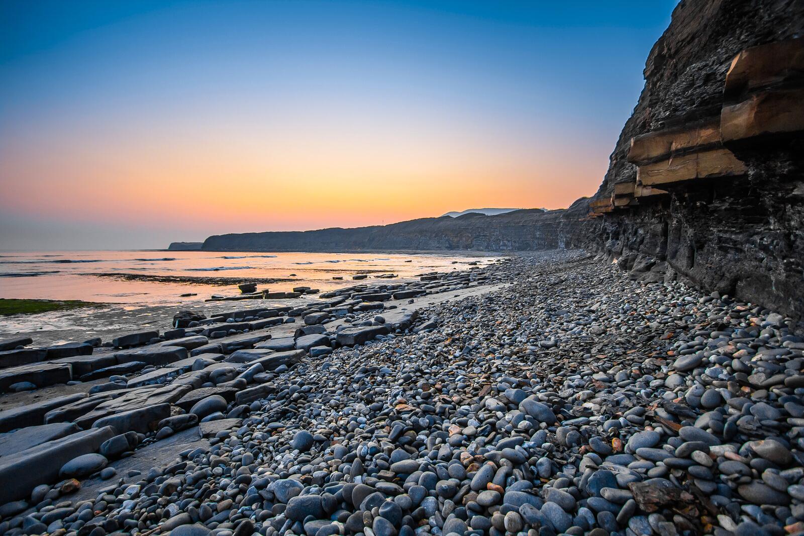 Бесплатное фото Море у подножья скалы на закате