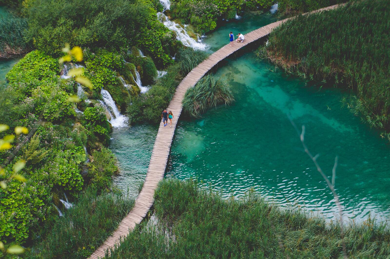 Free photo Tourists walk on a wooden bridge near a waterfall
