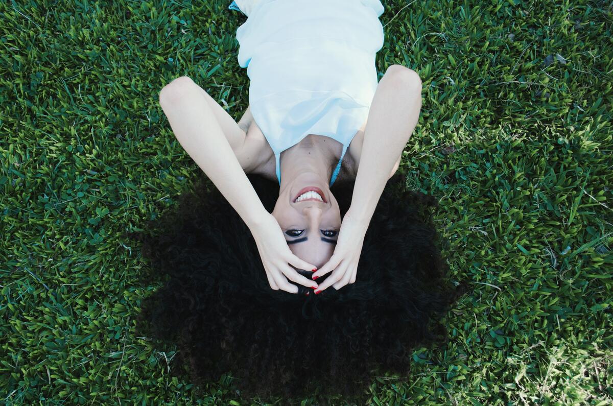 Красивая черноволосая девушка лежит на газоне