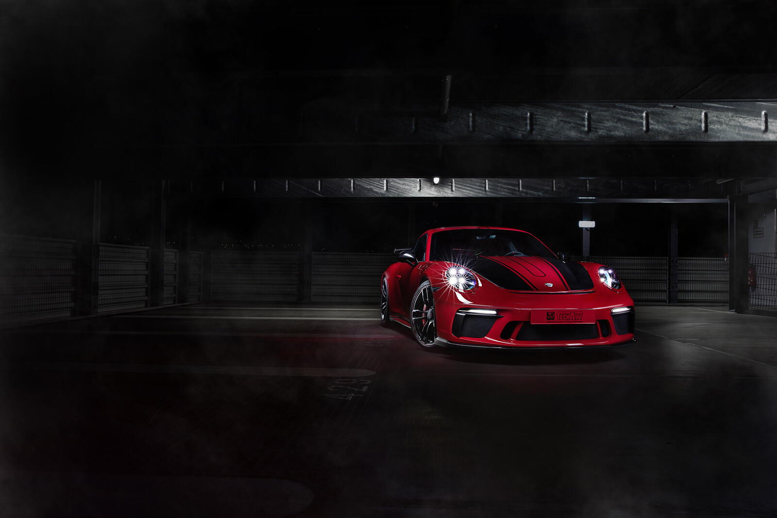 Бесплатное фото Красный с черными полосами Porsche 911 2018 года стоит в темном гараже