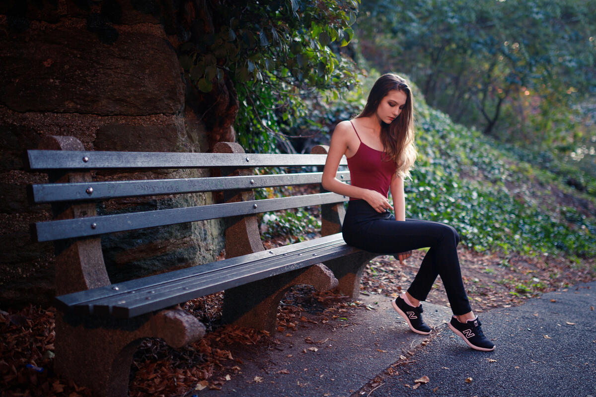 A girl in a red T-shirt sits on a bench