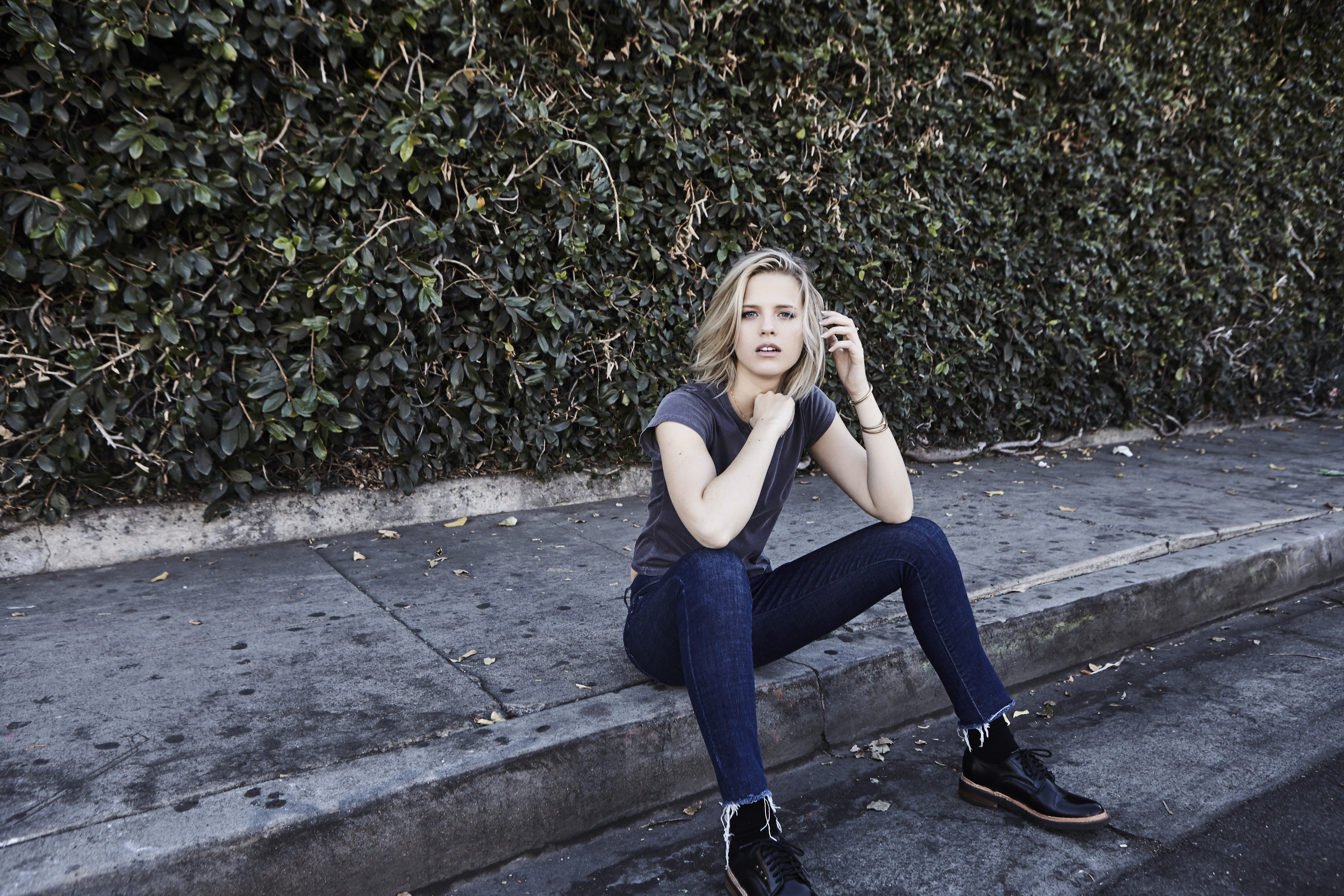 Бесплатное фото Светловолосая Молли Кейт Кестнер сидит на бордюре