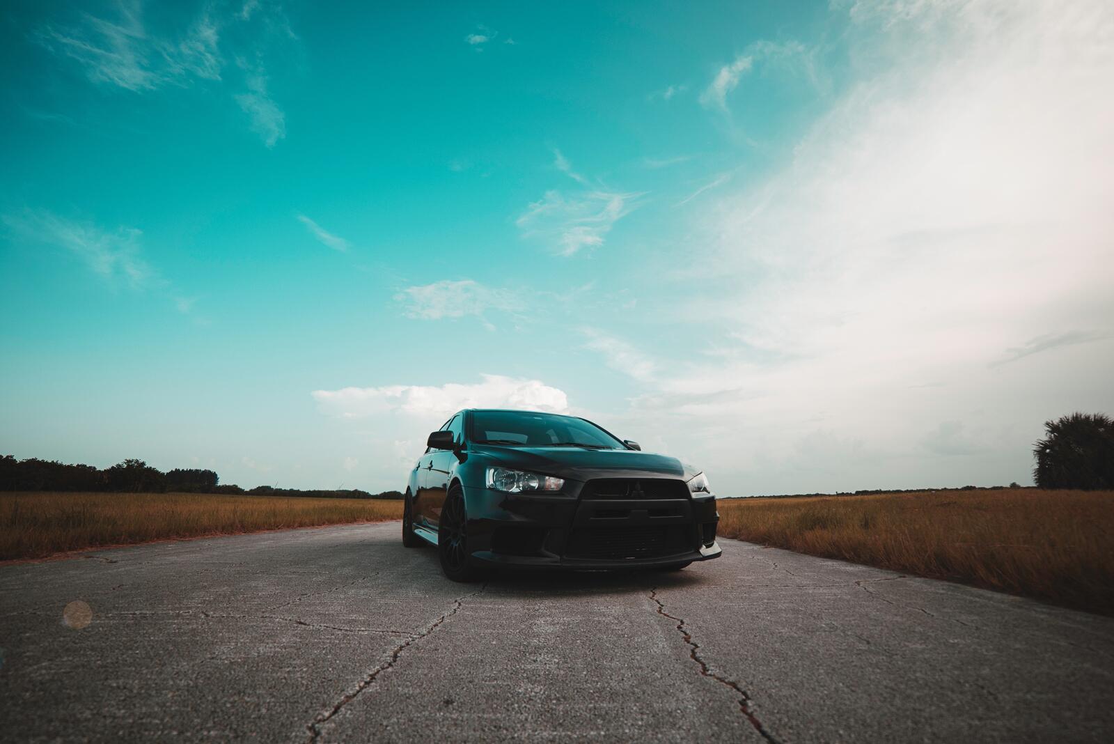 Free photo Black Mitsubishi Lancer on a country road in a field