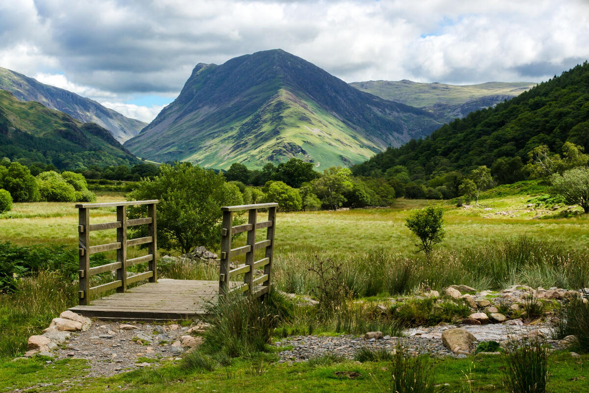 A bridge over a stream in England with mountains in the background
