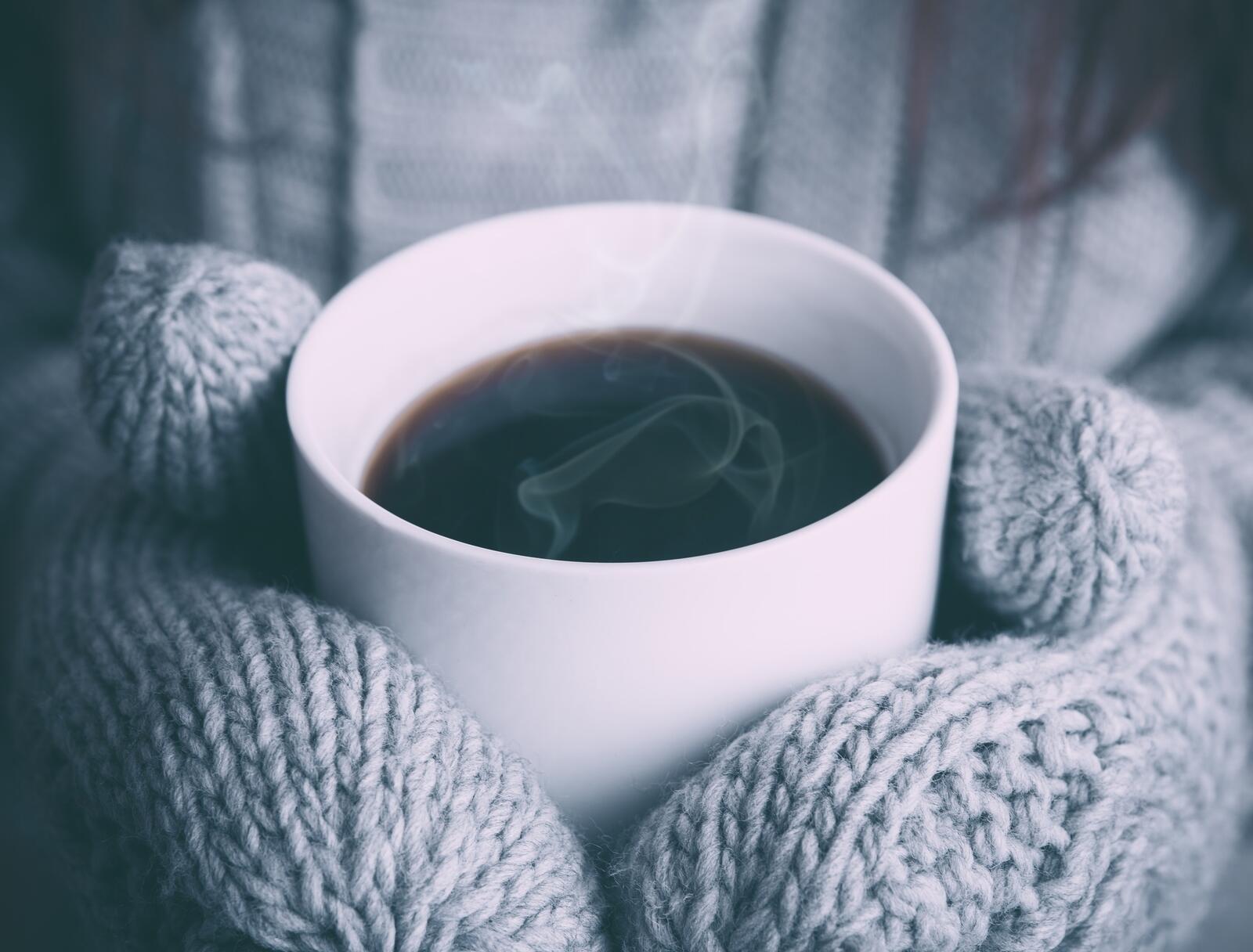 Free photo A cup of hot coffee in mittens.