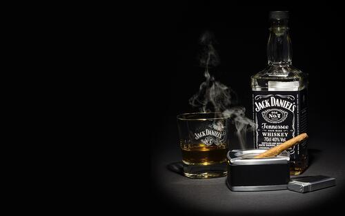 Jack Daniel`s Alcoholic Beverage on a Dark Background with a Smoking Cigar