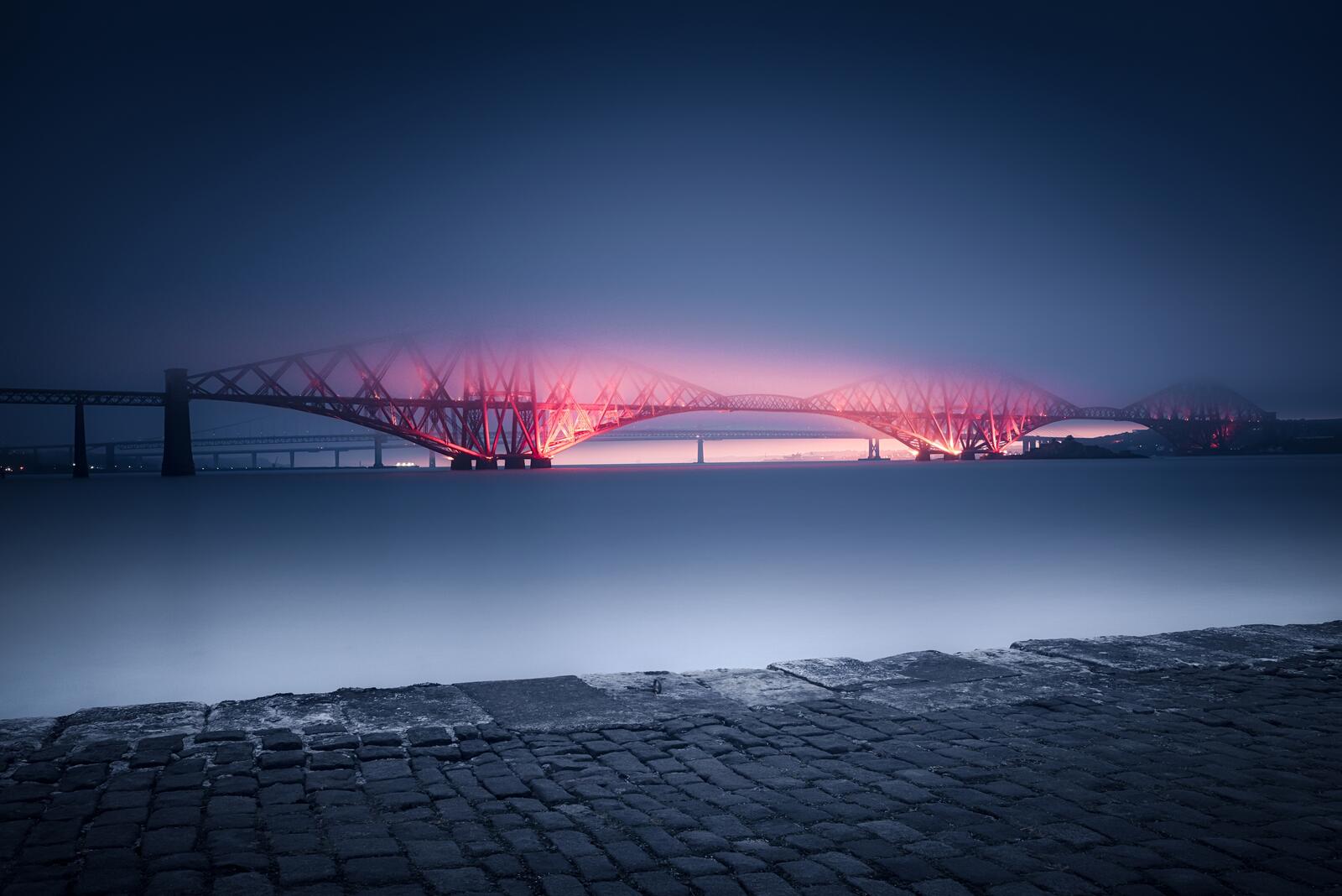 Бесплатное фото Шотландский мост во время заката в тумане подсвечивается красным светом