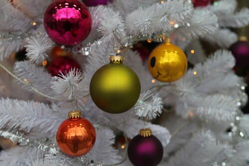 Разноцветные рождественские игрушки на белой новогодней елке