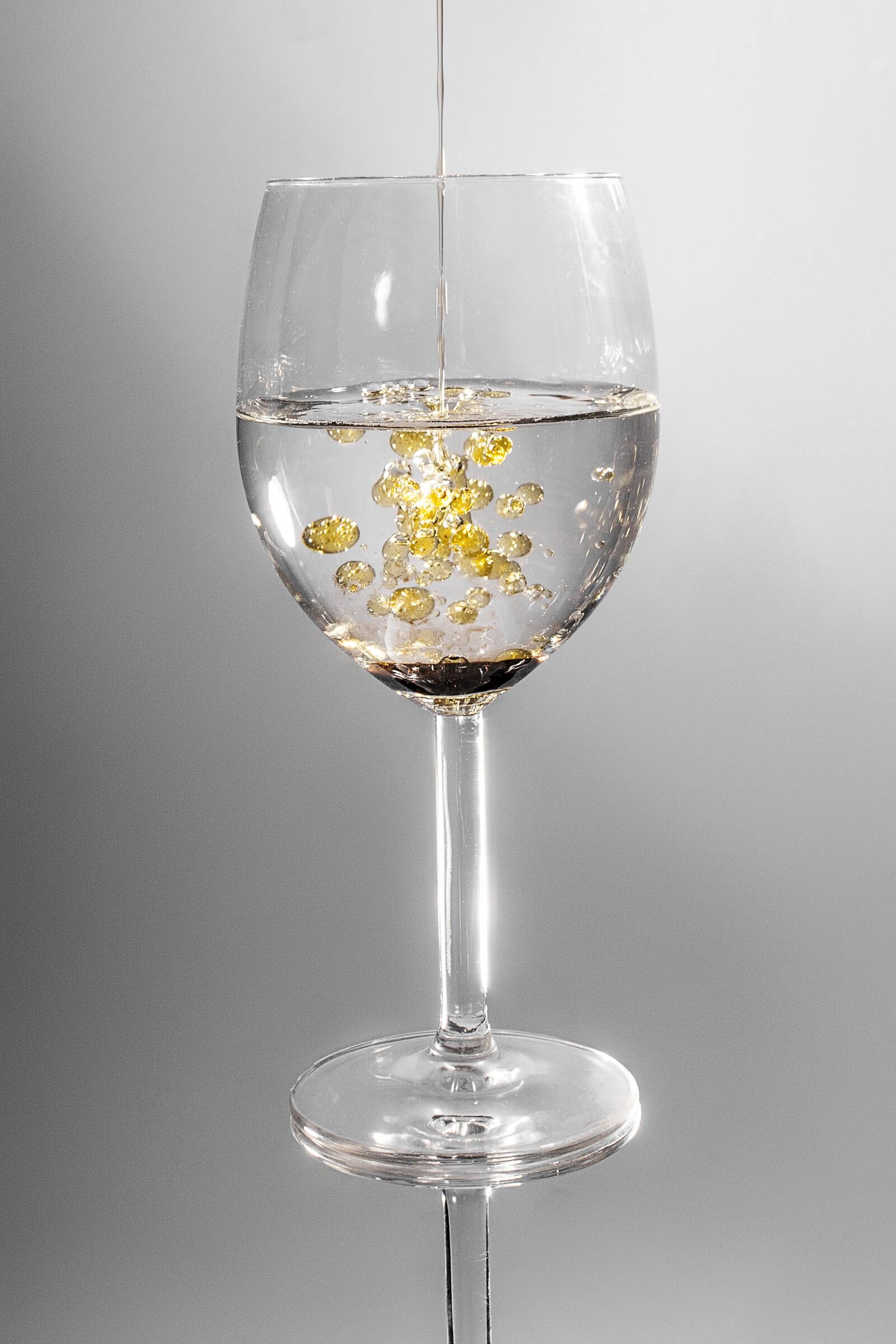 Free photo A glass with clear liquid and drops of oil