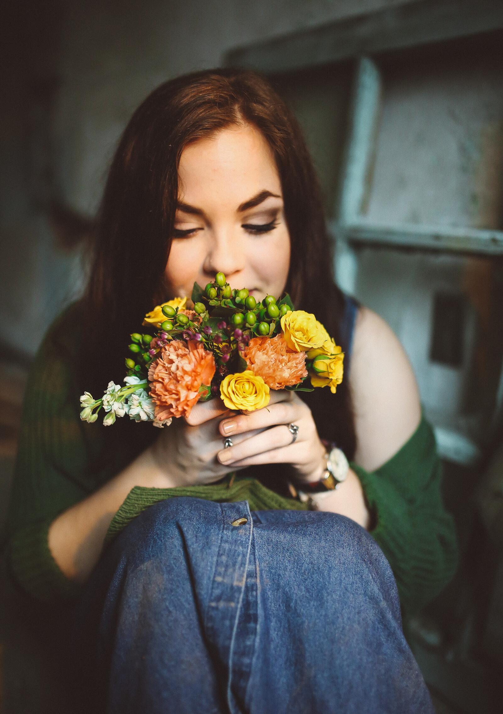 Бесплатное фото Темноволосая девушка любуется букетом цветов