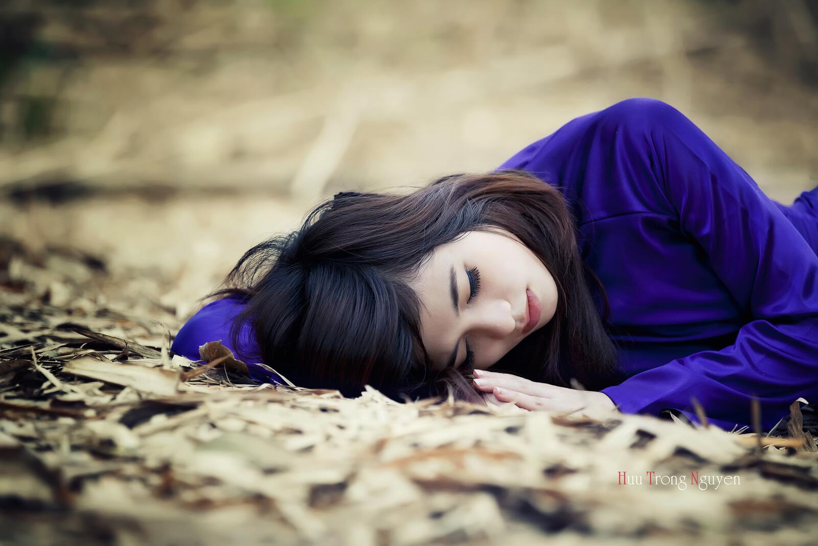 Бесплатное фото Темноволосая девушка в синем костюме лежит на земле