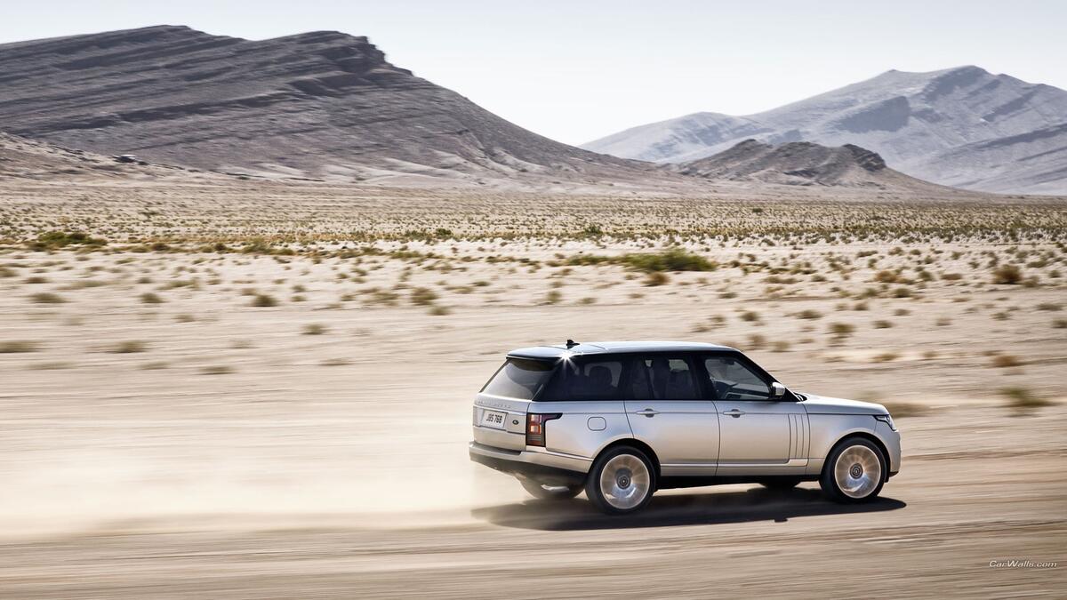 Range Rover driving through the dust at high speed.