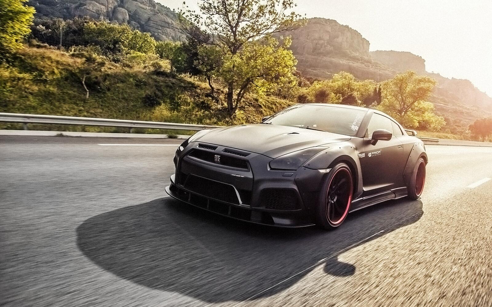Free photo A black Nissan GT-R R35 rushing down the road in the middle of the day.