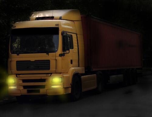 Yellow Manx truck with lights on in the dark.