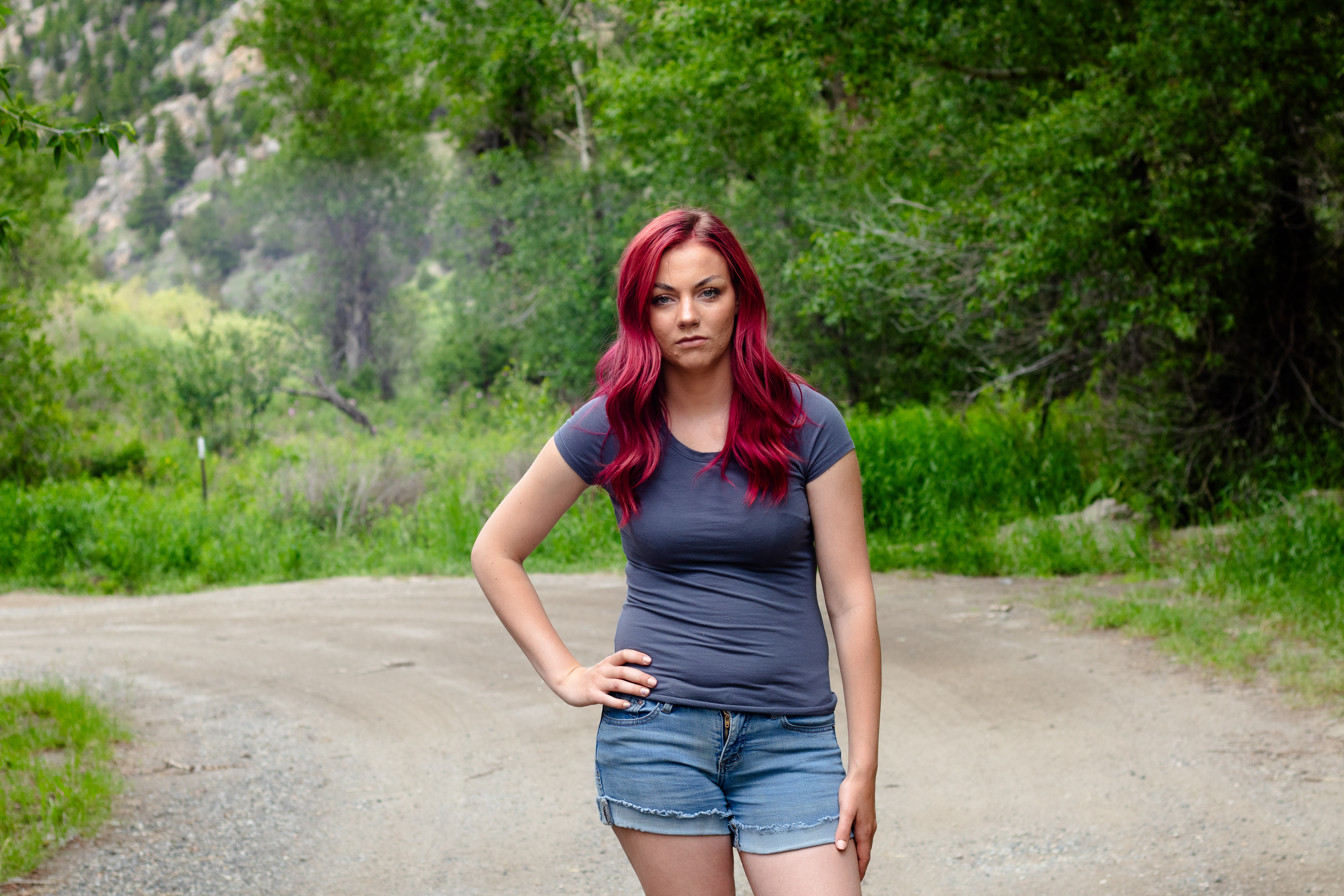 免费照片一个粉红色头发的女孩站在一条森林道路上
