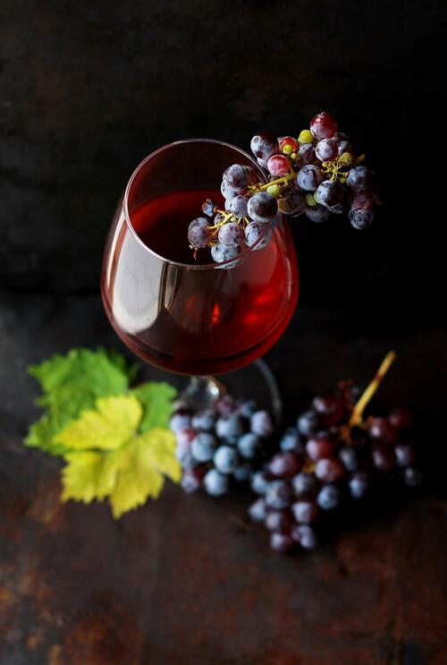 A glass of red wine and a bunch of grapes.