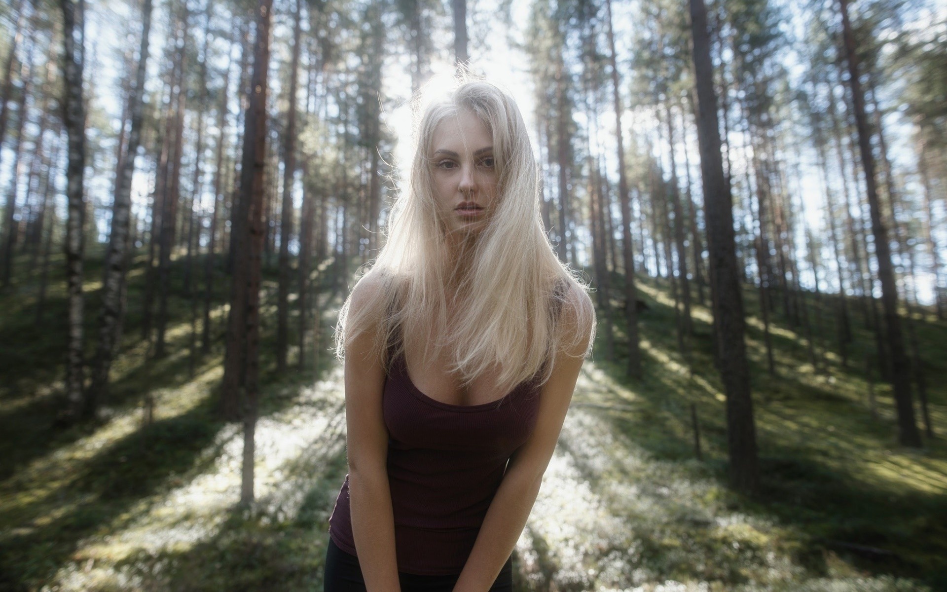 Бесплатное фото Белобрысая девушка в хвойном лесу в солнечную погоду