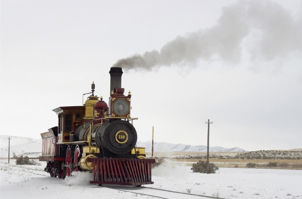 A steam locomotive runs on a winter railroad track