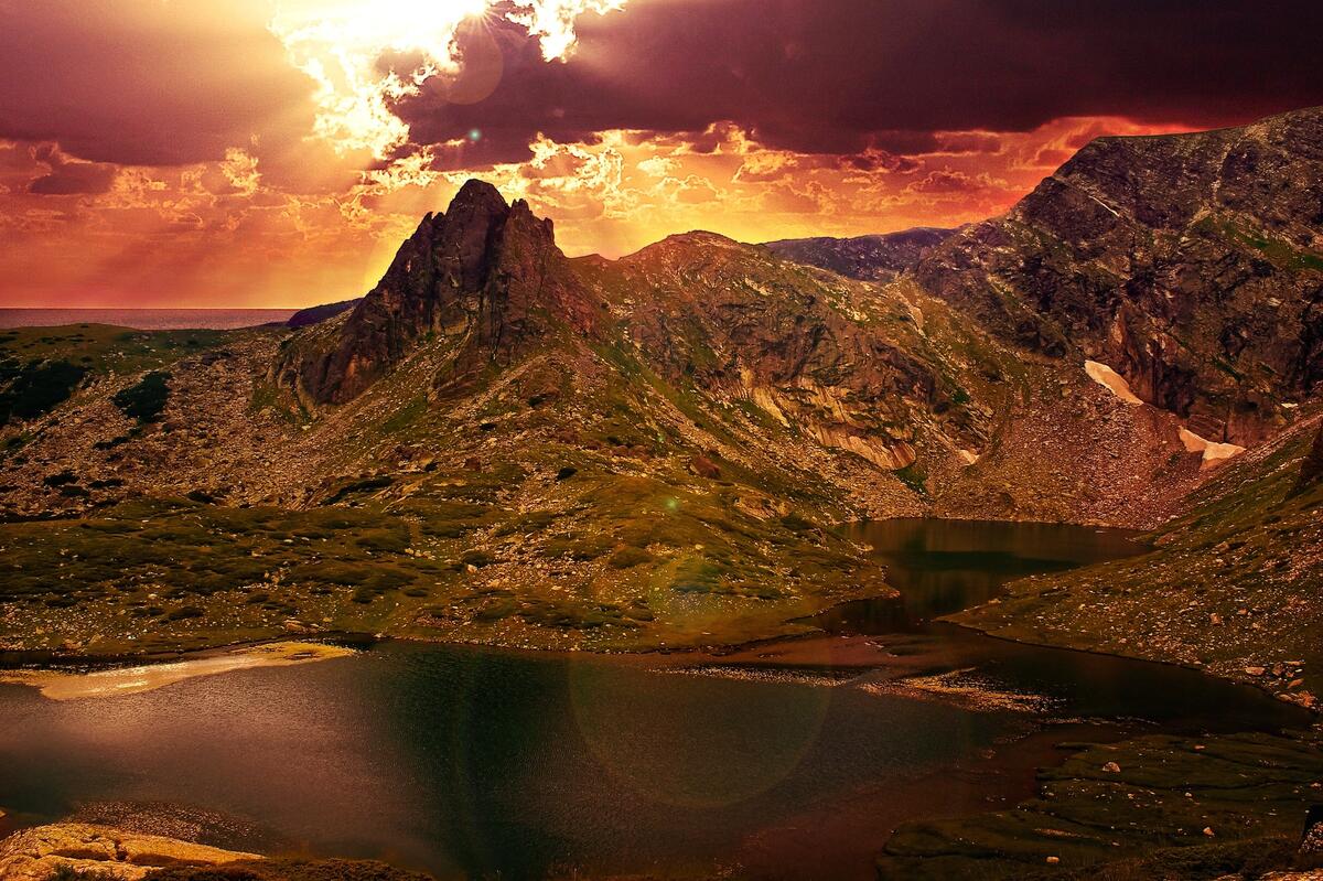 Bright orange sky with clouds over a mountainous area with a lake