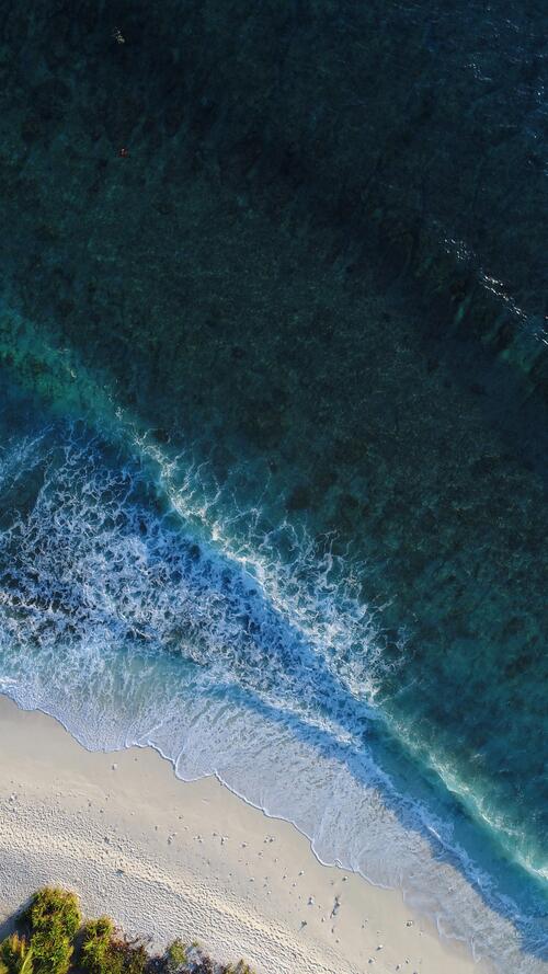 Морская волна разбивающаяся о песочный берег пляжа