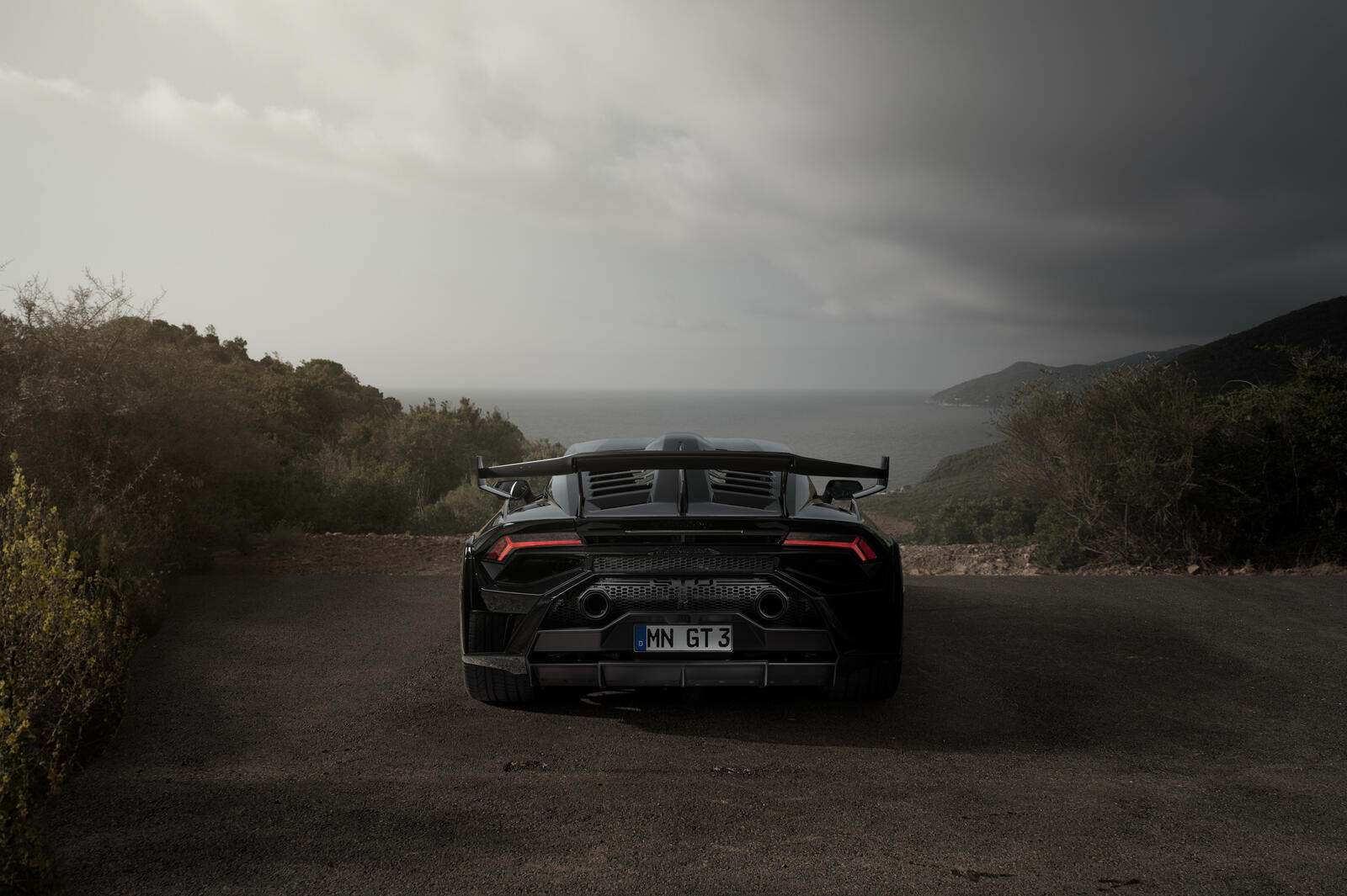 Бесплатное фото Черная Lamborghini Huracan STO на загородной дороге