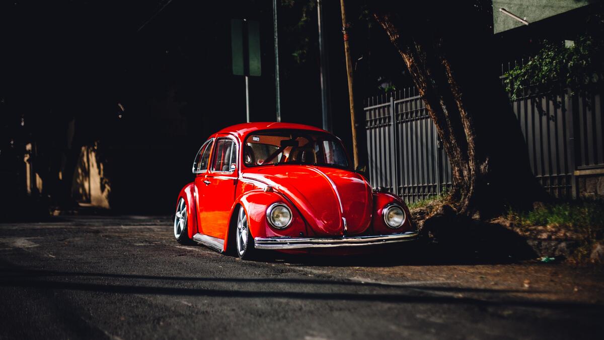 A red VW Beetle is parked on the side of the road.