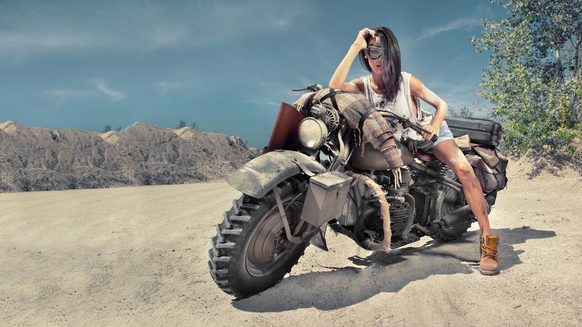 Girl poses in the desert on a vintage motorcycle