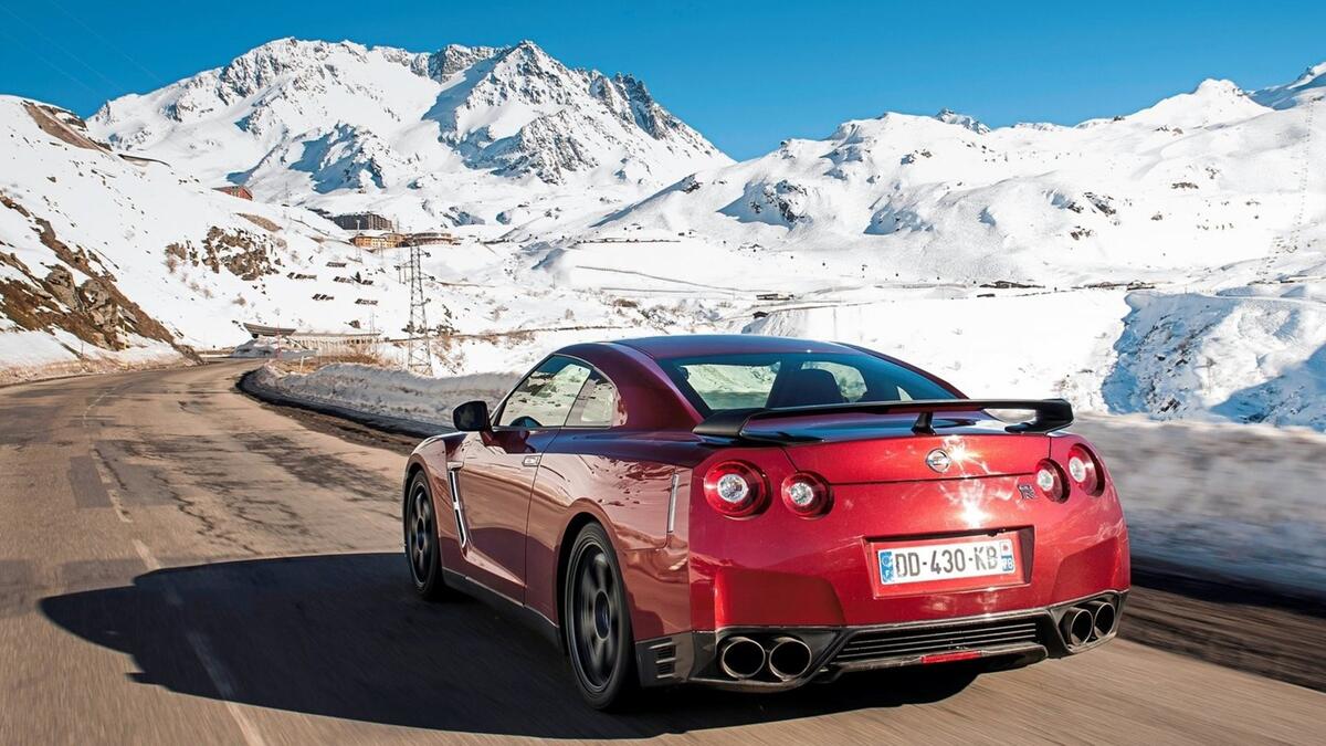 A red Nissan GTR against a backdrop of snowy mountains