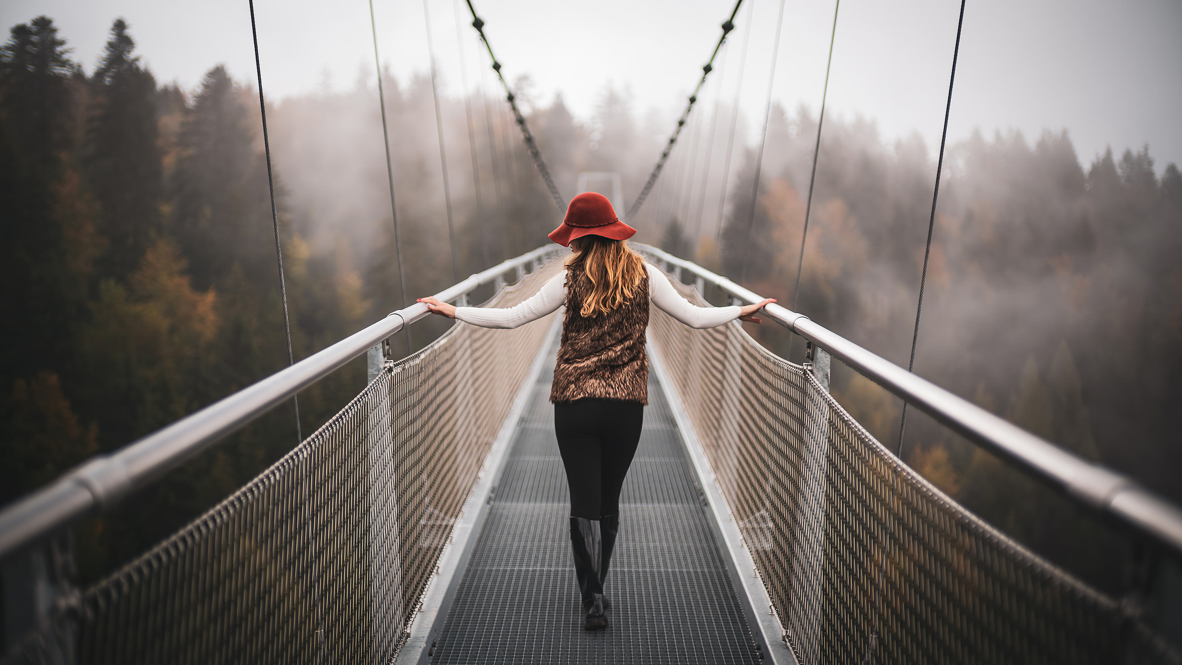一个戴帽子的女孩走过一座窄桥