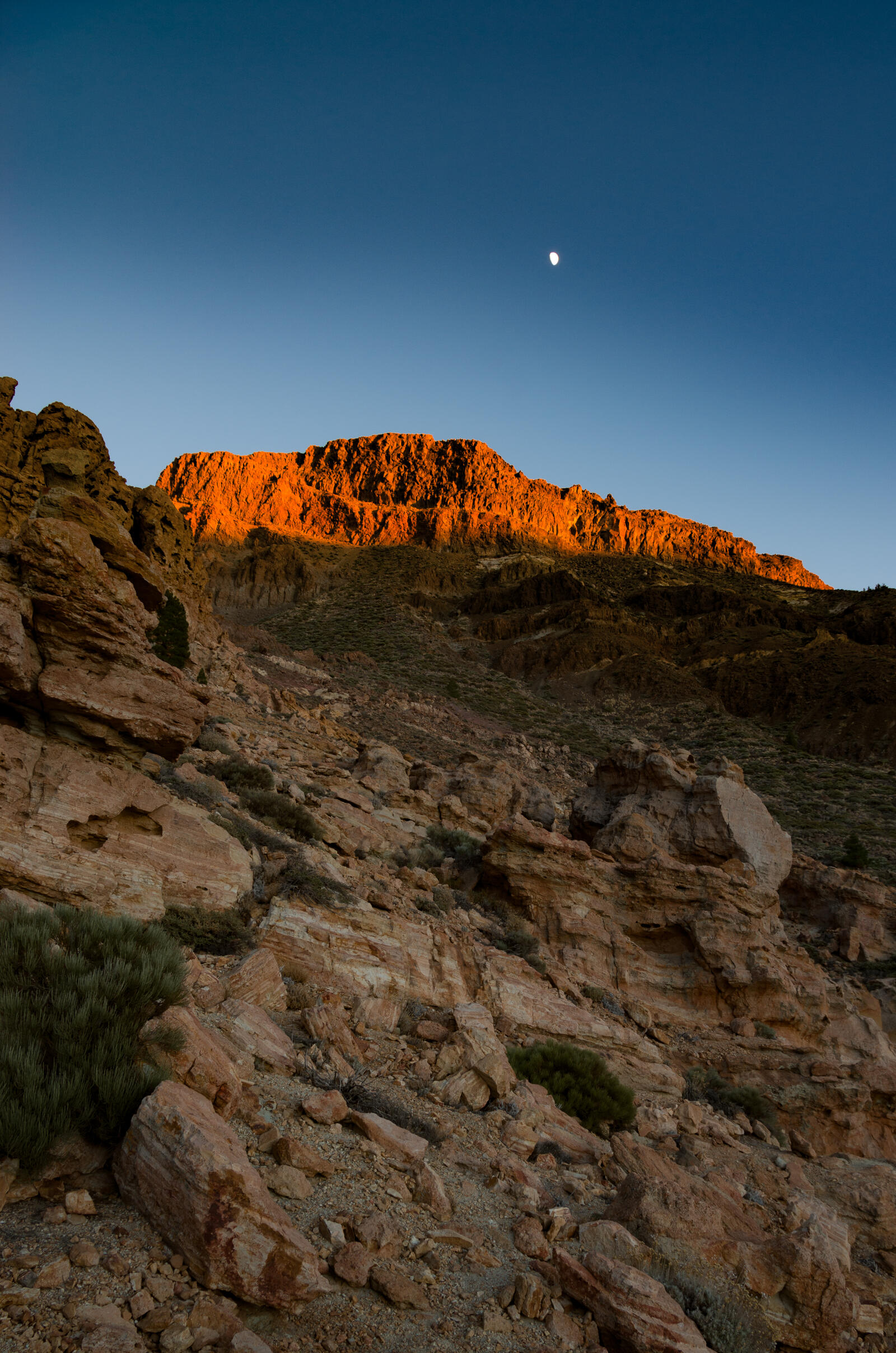 Бесплатное фото Солнце на закате освещает вершину скалы