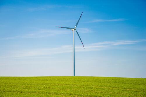 A lonely windmill in a field of green grass