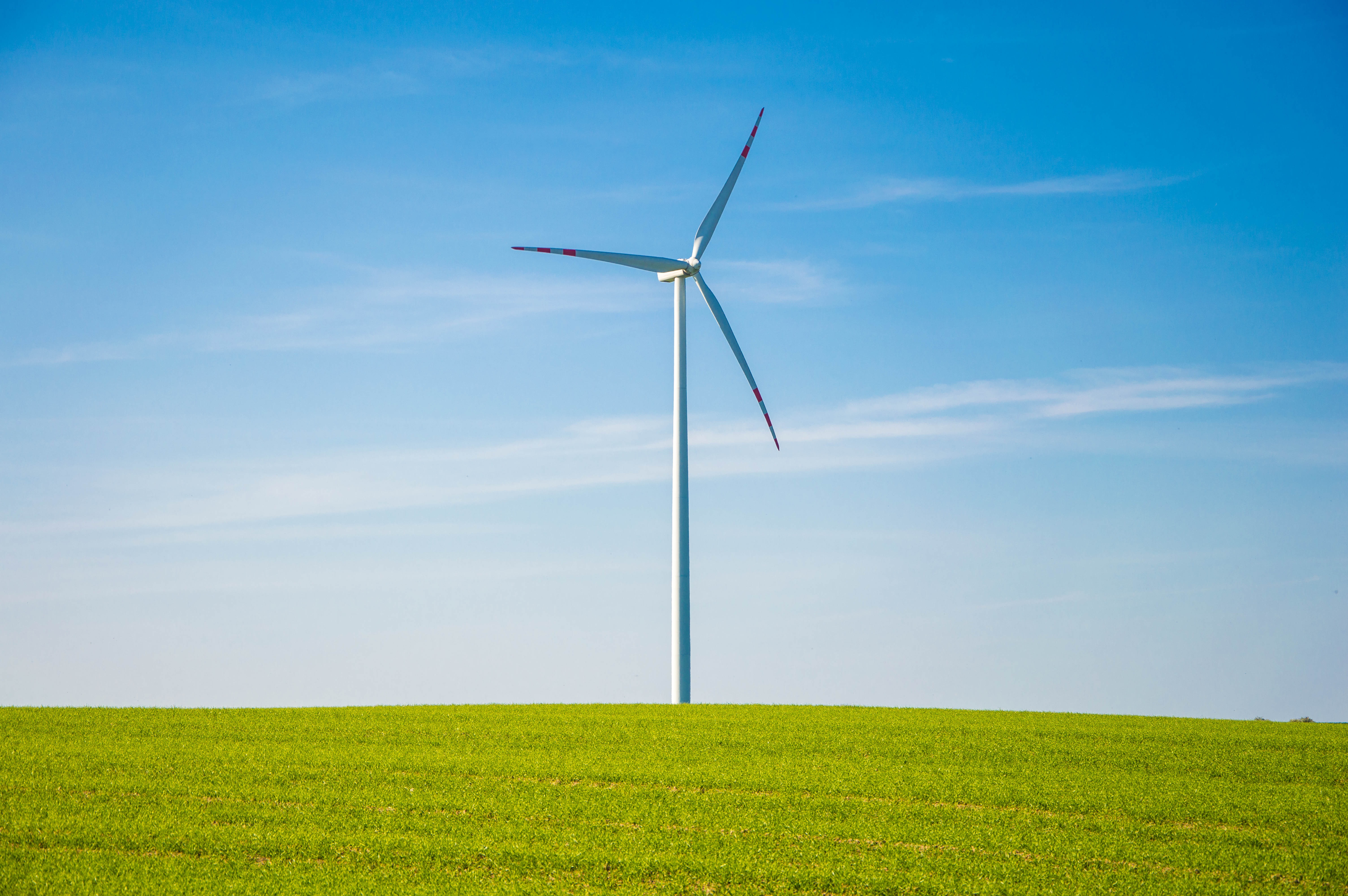 Бесплатное фото Одинокая ветряная мельница в поле с зеленой травой